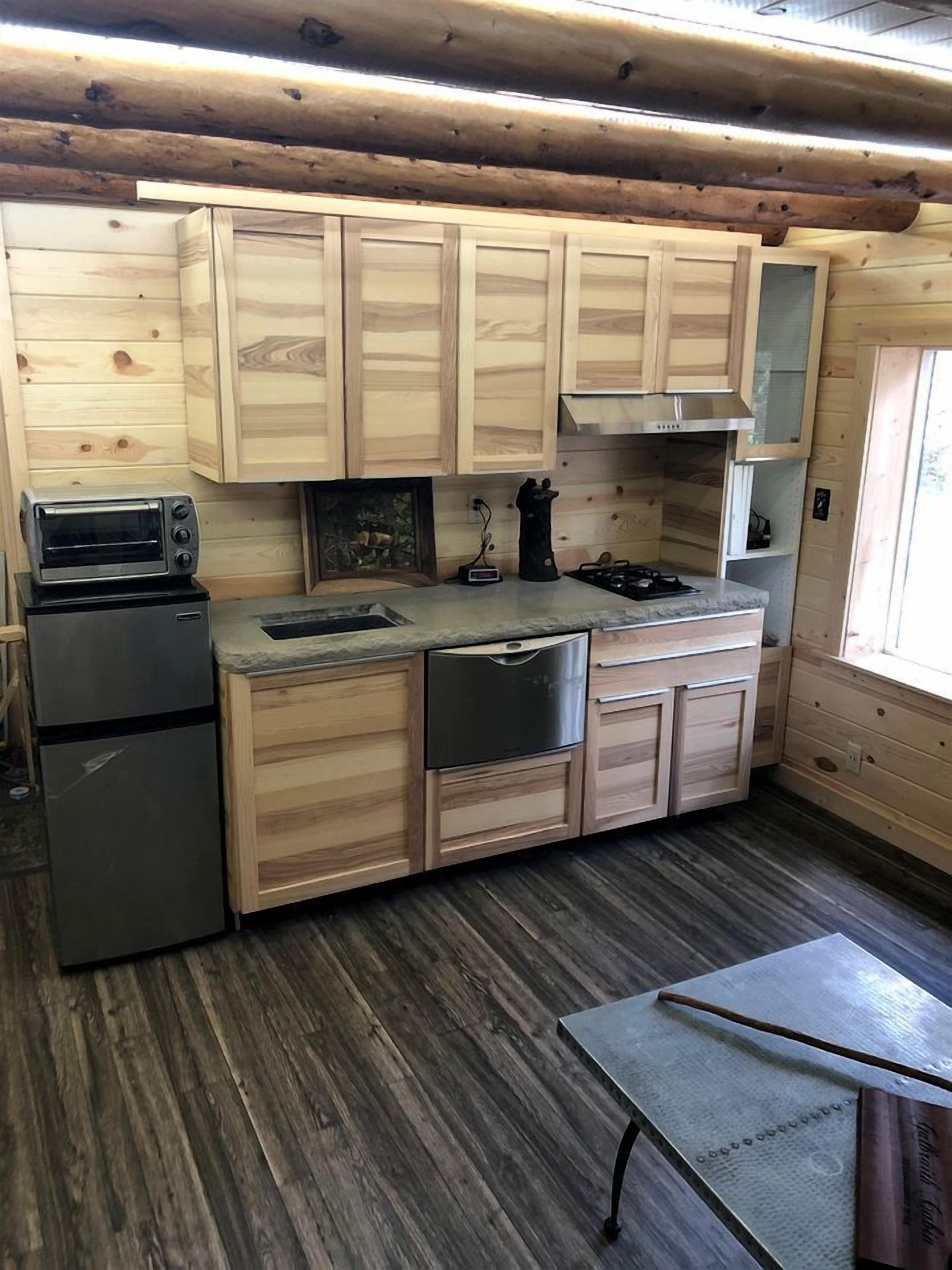 Une cuisine compacte avec des meubles en bois, une cuisinière encastrée, un évier et un petit réfrigérateur.