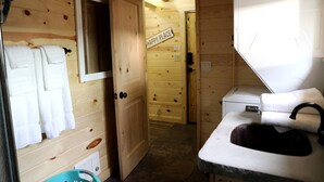 A wooden cabin interior with a bathroom featuring a sink, a towel rack, and a sign reading 'HAPPY PLACE'. - Peaceful Log Cabin Perfect for a Romantic Getaway near Yellowstone, Idaho (Island Park)