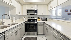 A modern kitchen with stainless steel appliances, white cabinetry, and a window providing natural light. - Formal dining room, warm and inviting bedrooms, and a large screened porch! (St. Augustine Beach)