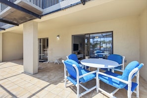 An outdoor patio with a round table and four chairs, a glass door leading to an interior space, and a tiled floor. - Formal dining room, warm and inviting bedrooms, and a large screened porch! (St. Augustine Beach)