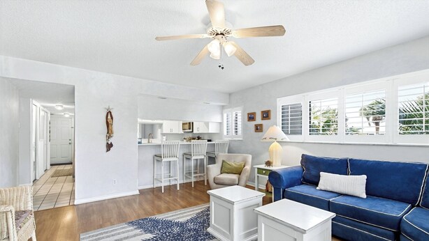 A living room with a blue sofa, white coffee table, and a ceiling fan. - Formal dining room, warm and inviting bedrooms, and a large screened porch! (St. Augustine Beach)