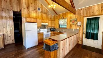 Una cocina con paneles de madera, un refrigerador blanco, una estufa, un microondas y un lavaplatos.