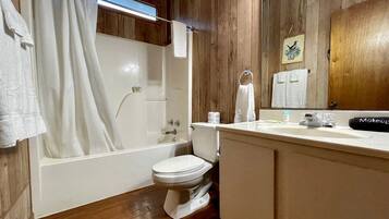 A bathroom with a bathtub, toilet, and vanity with a mirror.