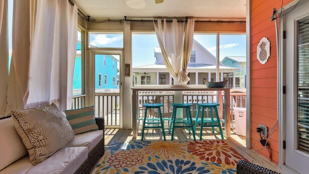 Een balkon met een bank, stoelen en een vloerkleed met een patroon.