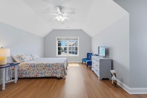 Ein Schlafzimmer mit Bett, Schminktisch, Sessel, Fernseher und Deckenventilator.