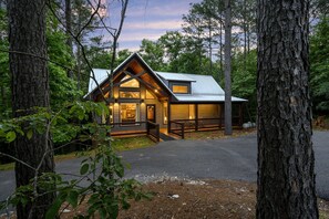 A cabin with a front porch, large windows, and a garage. - Blue Magnolia (Broken Bow)