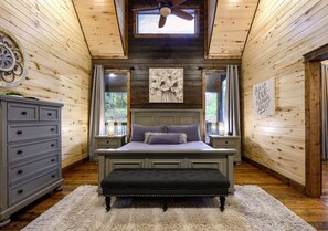 Ein Schlafzimmer mit Bett, Sitzbank, Kommode und Deckenventilator.