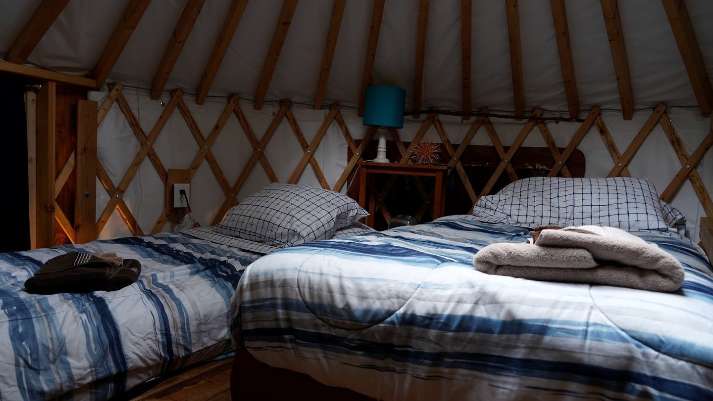 A tent-style room with two beds, a lamp, and a small table.