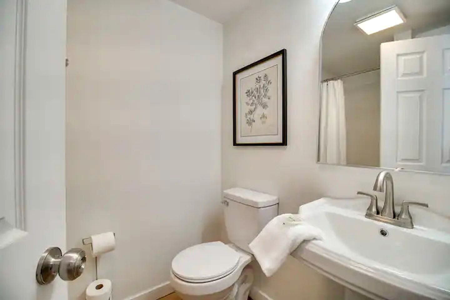 Une salle de bain avec des toilettes, un lavabo et un tableau encadré au mur.