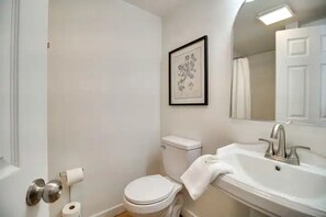 Ein Badezimmer mit Toilette, Waschbecken und einem gerahmten Bild an der Wand.