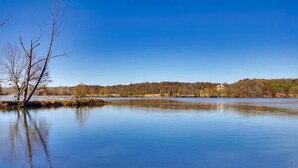 Un lago tranquilo con cielo despejado, árboles y una orilla lejana.