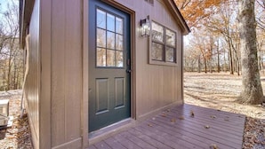 A small wooden building with a dark door, a window, and a wooden deck.
