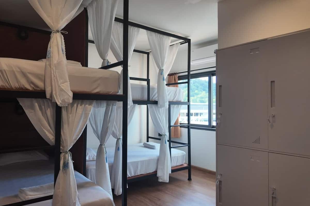 A dormitory room with bunk beds, a wardrobe, and a window with a view.