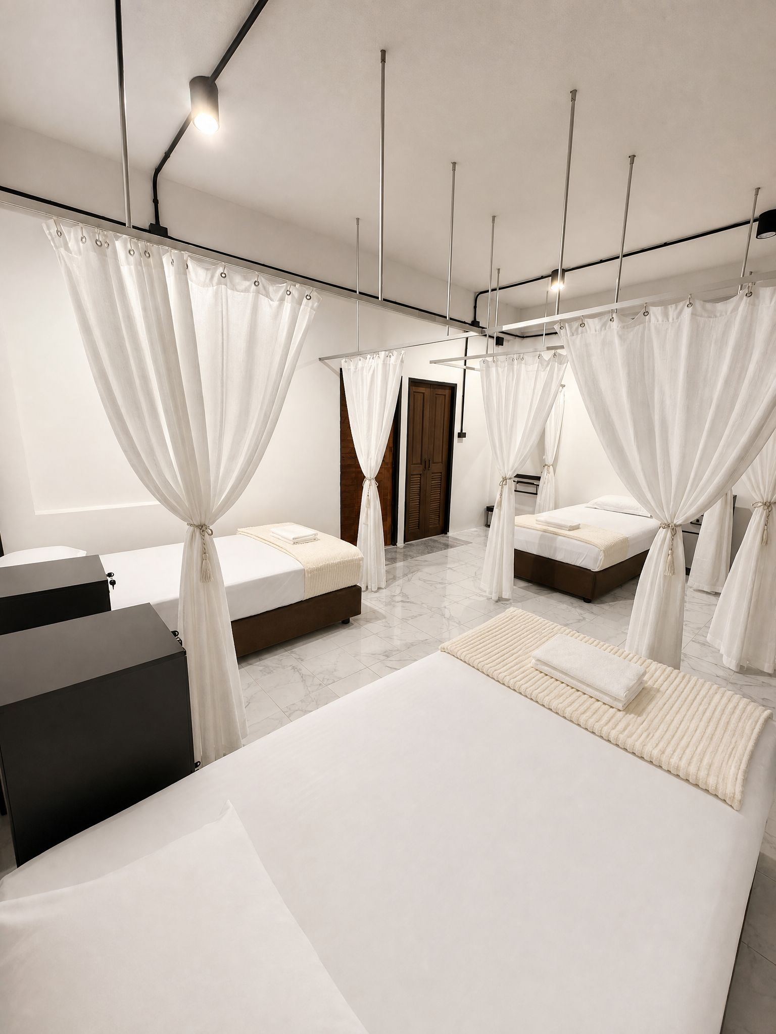 Un dormitorio moderno con dos camas, cada una con dosel, un ventanal grande y un aparador negro.