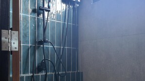 A shower with a handheld showerhead and a wall-mounted control panel.