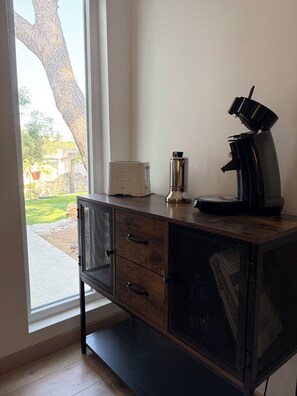 Una cuina americana amb torradora, cafetera i un armari amb calaixos.