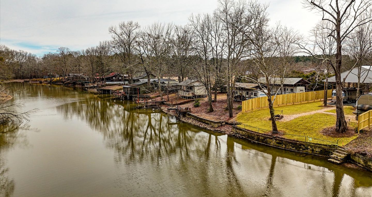 A riverside property with cabins, a dock, and a fenced area.