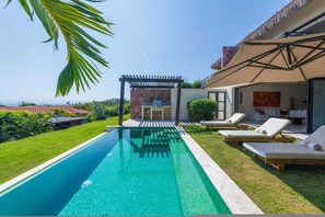 Ein Swimmingpool mit Liegestühlen, einer Pergola und Blick auf den Ozean.