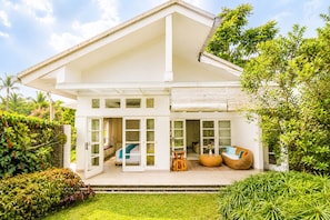A two-story house with a balcony, a covered patio, and a garden.