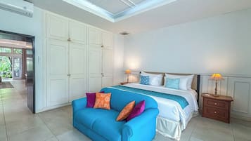Un dormitorio con cama, un sofá azul y una mesita de noche con lámparas.