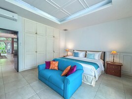 Ein Schlafzimmer mit einem Bett, einem blauen Sofa und einem Nachttisch mit Lampen.