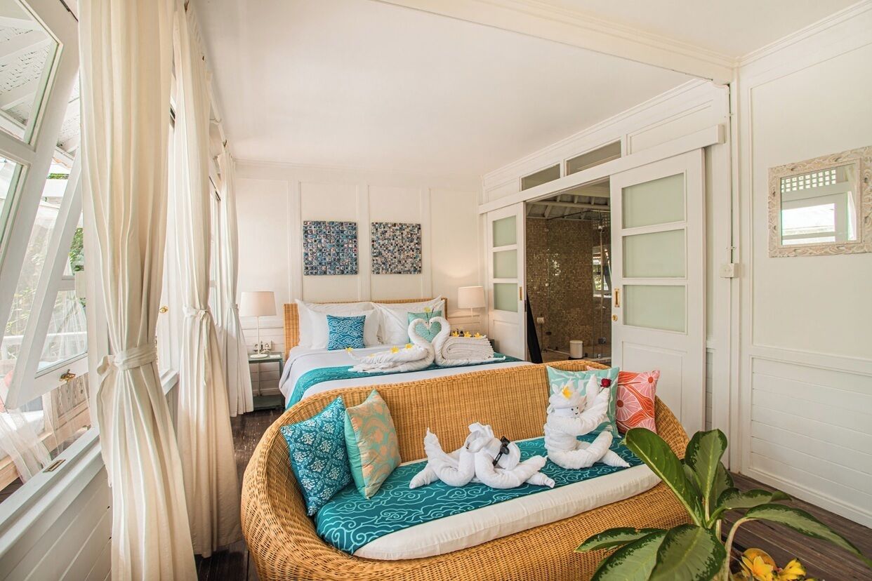 Une chambre d’hôtel avec deux lits, un canapé et une grande fenêtre avec des rideaux.