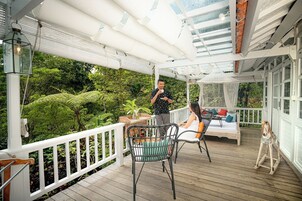 Eine Holzterrasse mit weißer Brüstung, einem Tisch und zwei Stühlen.