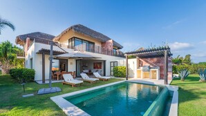 A modern house with a swimming pool, a patio with lounge chairs, and a thatched roof. - Villa Turquesa in Punta Mita (Punta de Mita)