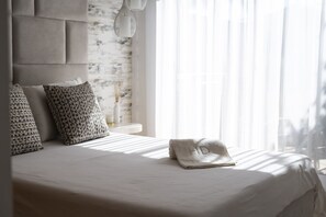 A neatly made bed with a folded towel, a headboard, and patterned pillows. - Golf Garden by Hd properties (Vilamoura)