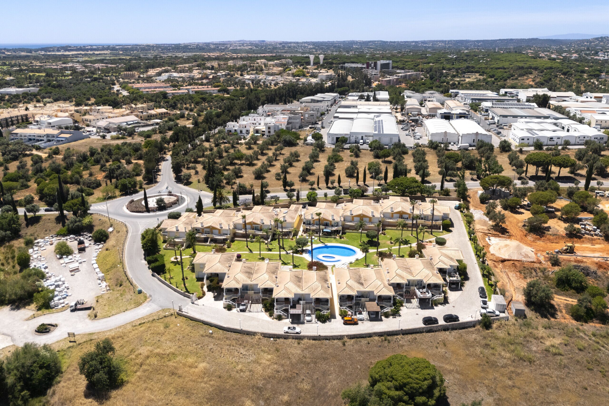 Una vista aerea di un quartiere residenziale con piscina, diversi edifici e una strada.