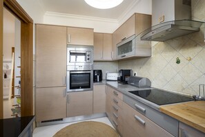 A modern kitchen with stainless steel appliances, wooden cabinets, and a glass backsplash. - Golf Garden by Hd properties (Vilamoura)