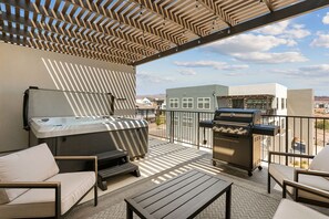 A balcony with a grill, seating, and a view of buildings. - Butter by the Beach: Desert Color Lagoon + Beaches (St. George)