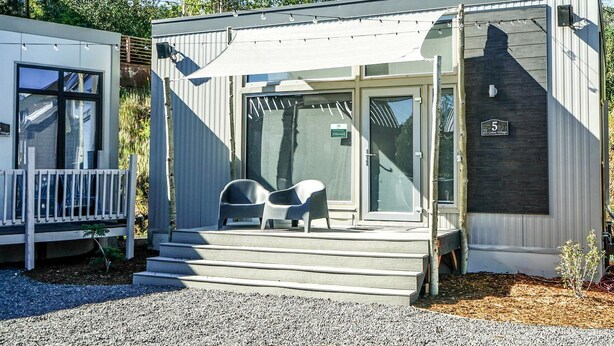 A modern cabin with a porch, a sliding door, and a small outdoor seating area.