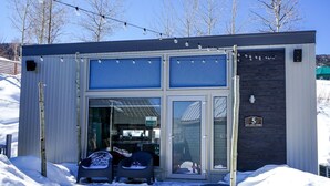 A modern building with a glass entrance, a sign indicating it's a ski lodge, and a number '5' on the side.