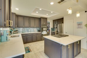 A modern kitchen with dark cabinets, a marble island, stainless steel appliances, and pendant lighting. - Hot Tub! Extended Escape 9 Mi to Oceanside Beach (Oceanside)