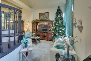 Ein geräumiges Wohnzimmer mit einer imposanten Treppe, einem Kamin und einem geschmückten Weihnachtsbaum.