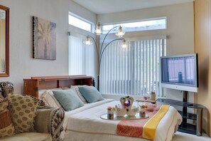 Ein Hotelzimmer mit Bett, Fernseher, Schreibtisch und einem Fenster mit Jalousien.