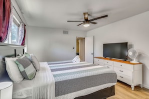 Ein Schlafzimmer mit einem Bett, einem Fernseher, einem Ventilator und Deckenventilator.