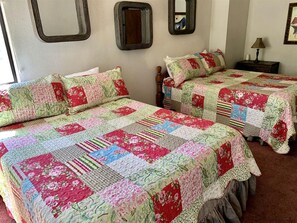 Zwei Betten mit Blumenquilts, ein Spiegel und eine Lampe auf einem Nachttisch.