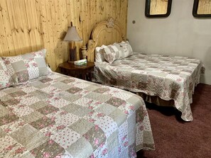 Ein Schlafzimmer mit zwei Betten, einem Holzkopfende, einem Nachttisch mit Lampe und einem Fenster mit Blick.