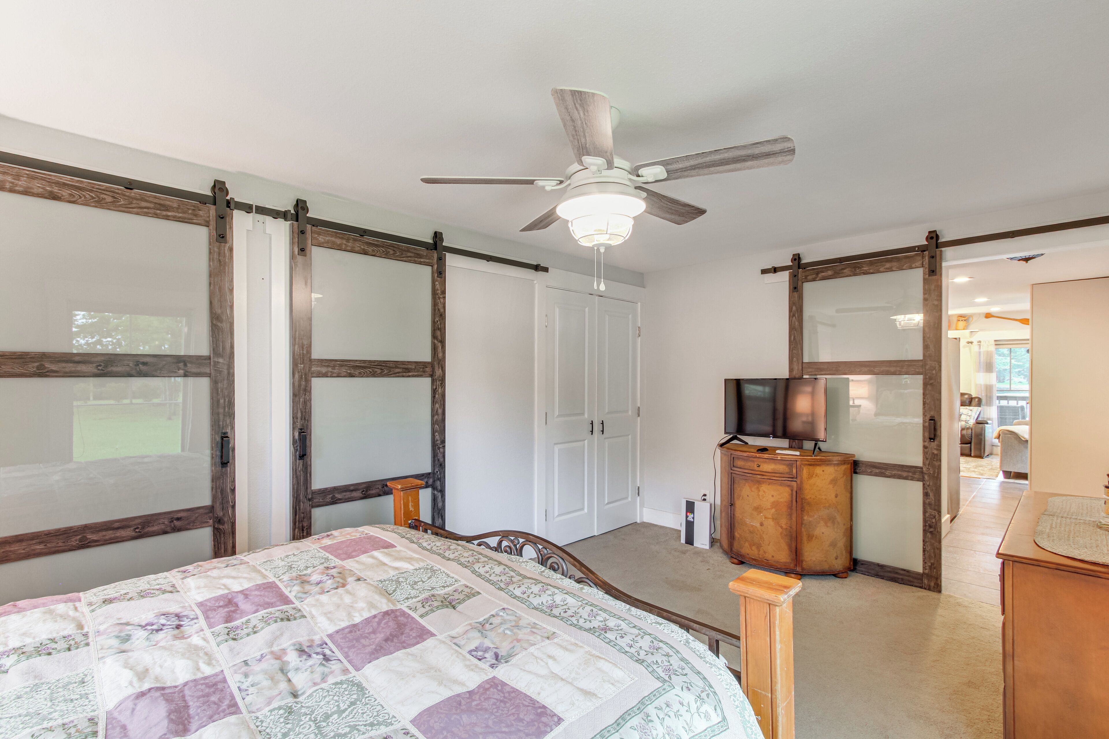 Une chambre à coucher avec un lit, un ventilateur de plafond, une télévision et une armoire en bois.