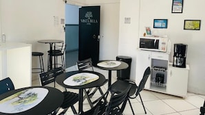 A compact room with a kitchenette, a microwave, a coffee maker, and a door with a logo. - Vista Bela Hotel Pindamonhangaba  (Pindamonhangaba)