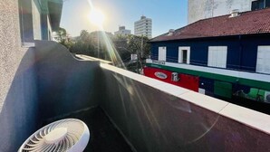 A balcony with a chair, a building labeled 'DENTISTAS,' and a clear sky with the sun. - Vista Bela Hotel Pindamonhangaba  (Pindamonhangaba)
