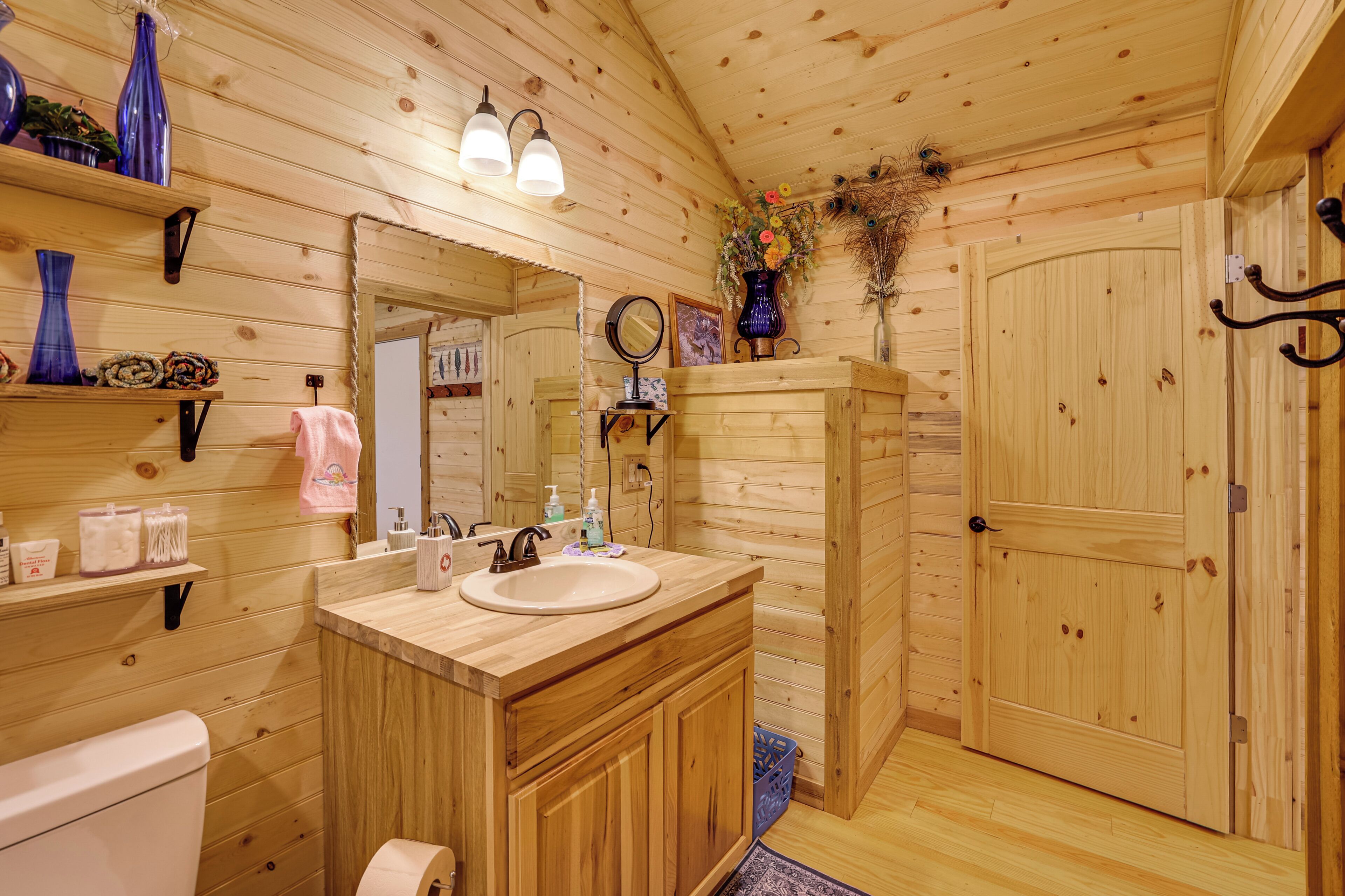 Une salle de bain de style rustique, avec des murs en bois, un meuble-lavabo en bois, un lavabo et des toilettes.