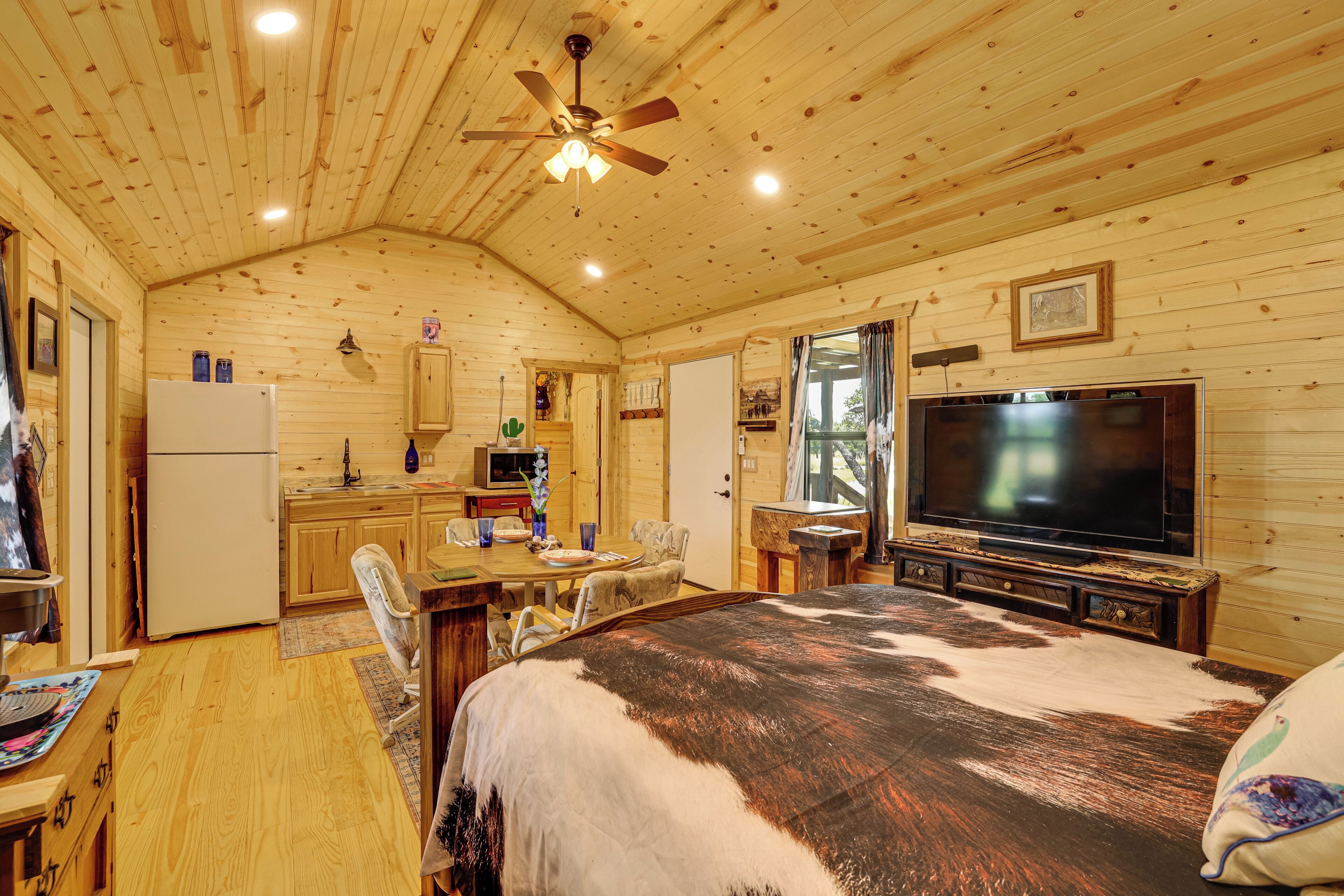 L’intérieur d’un chalet en bois comprend un lit, un téléviseur, un coin repas et une cuisine.