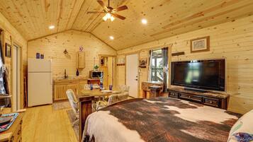 L’intérieur d’un chalet en bois comprend un lit, un téléviseur, un coin repas et une cuisine.