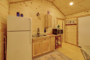 Ein Interieur einer Holzhütte mit Küchenbereich, inklusive Kühlschrank, Spüle, Mikrowelle und Holzschränken.