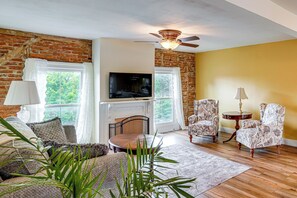 A living room with a fireplace, television, and patterned armchairs.