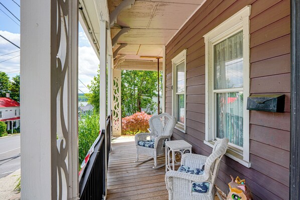 A porch with wicker furniture and a view of the street.
