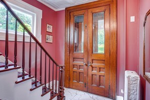 A staircase leading to a wooden door with glass panels, a white radiator, and framed artwork on the wall.